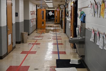 A school hallway is littered with ceiling tile and debris