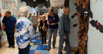 Elderly couples walk through a school hallway