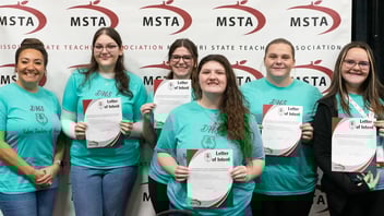 A group of high school FTA students hold signed letters of intent stating they intend to go into the teaching profession