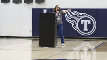 Jennifer Jones speaks from a podium inside a school gymnasium