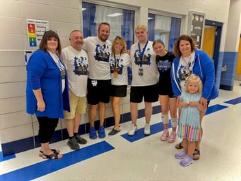 Eight people stand in a school hallway