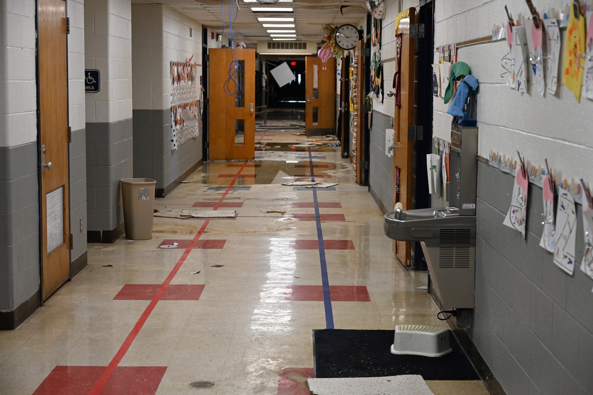 A school hallway is littered with ceiling tile and debris