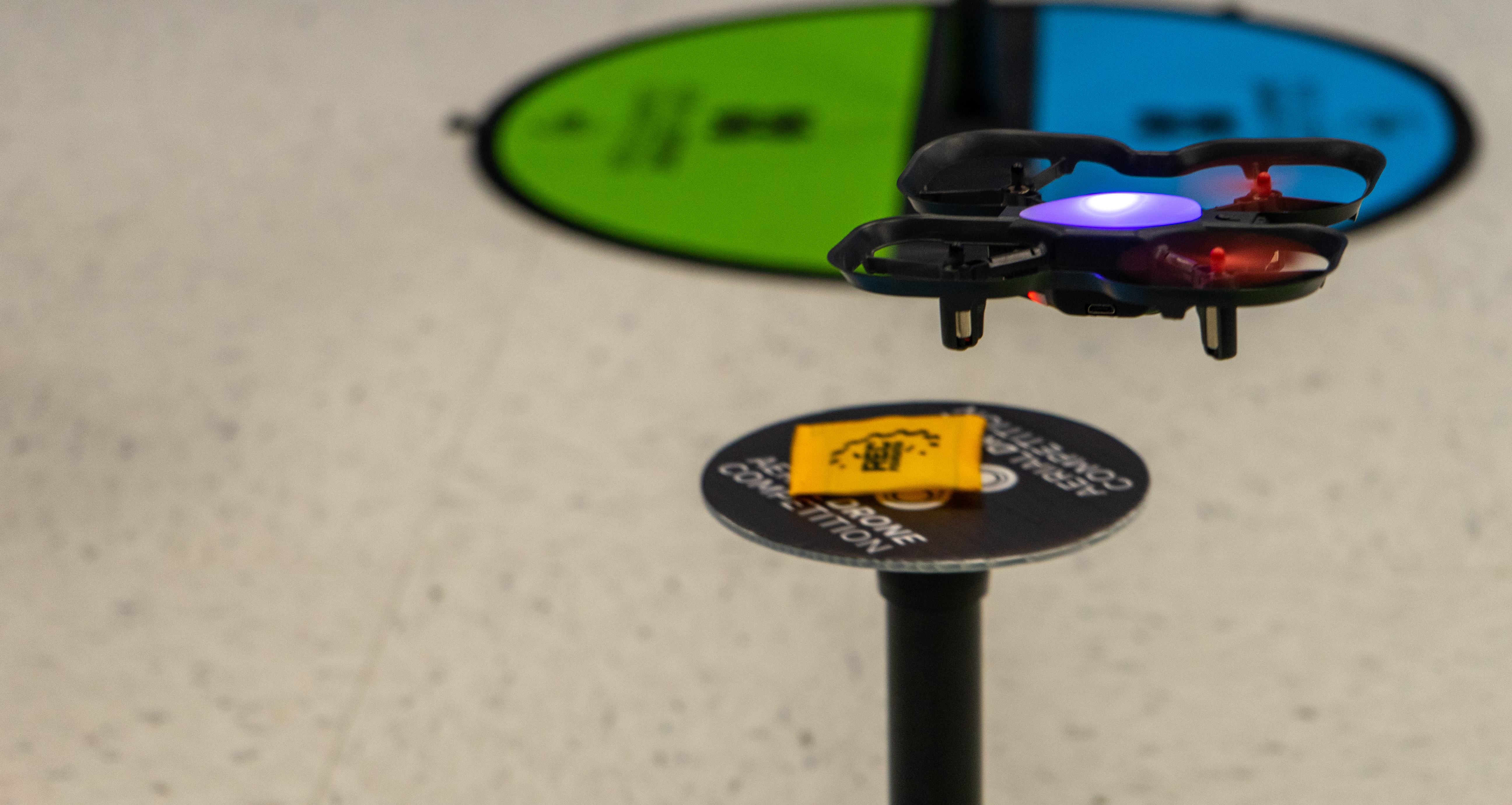 A small, black drone flies through a drone course