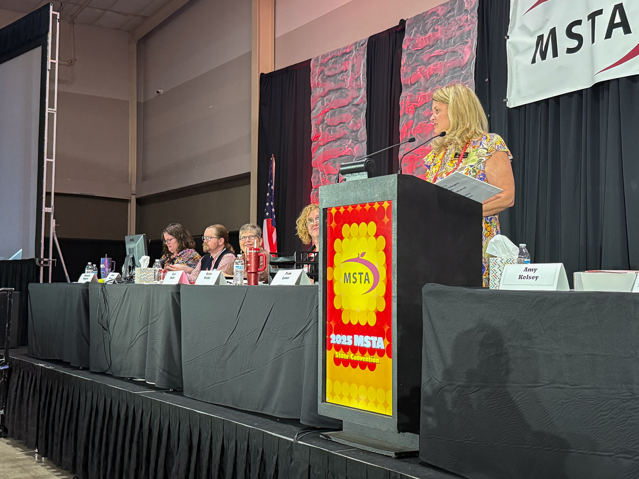 Amy Kelsey stands at a podium