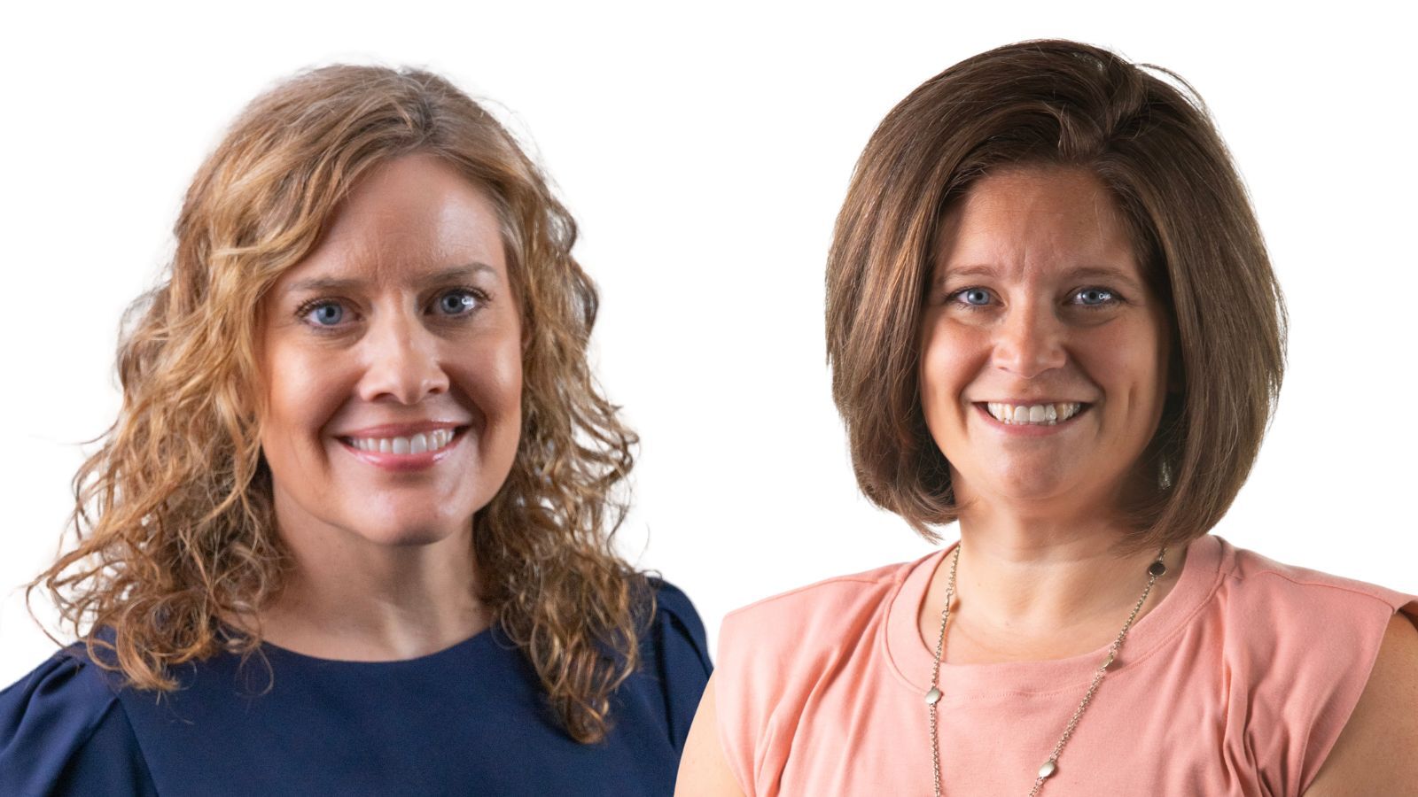 A woman in a blue shirt and blonde curly hair stands next to a woman in a pink shirt with short brown hair