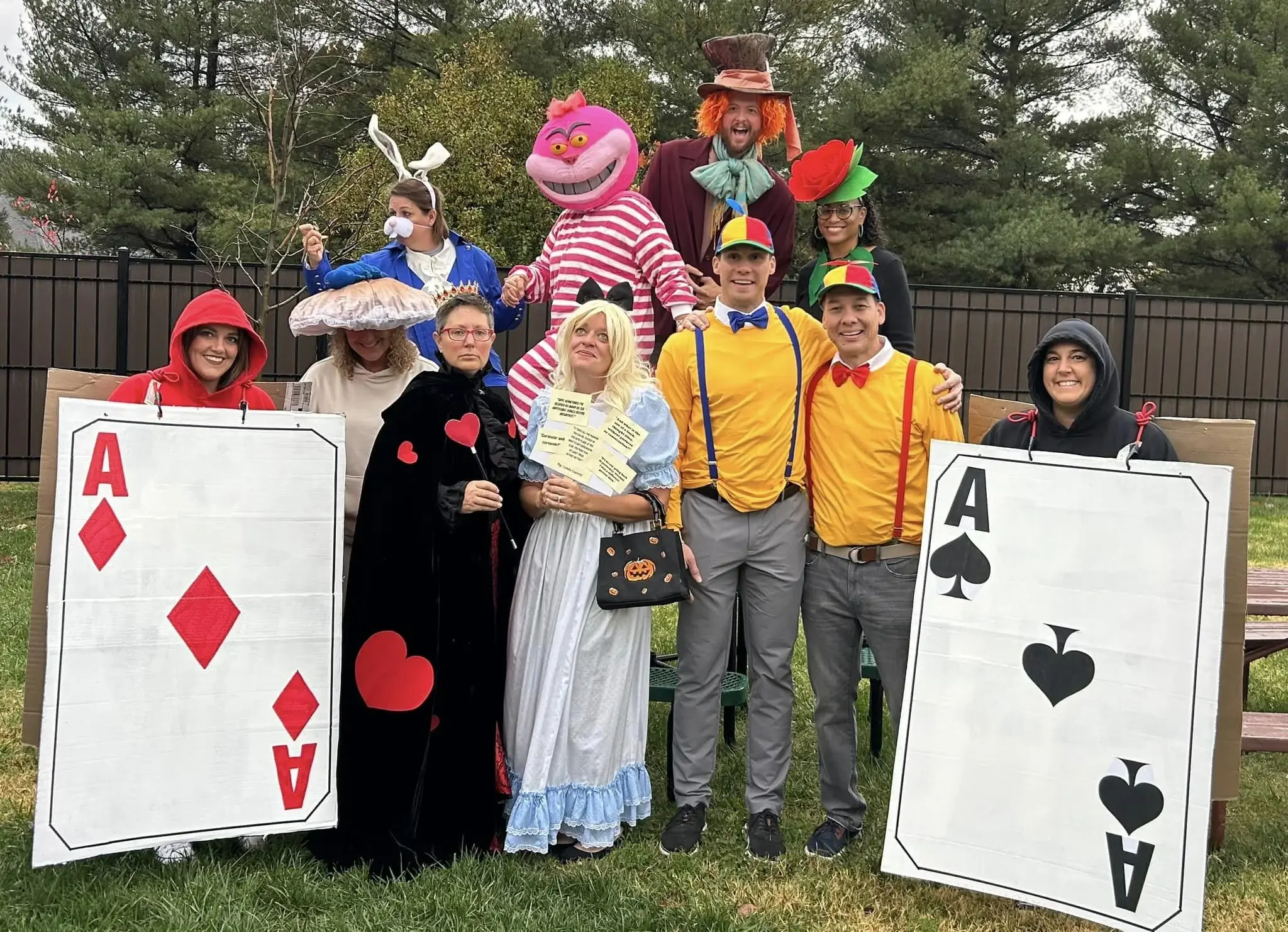 A group of teachers pose together, all dressed as characters from the move "Alice in Wonderland."