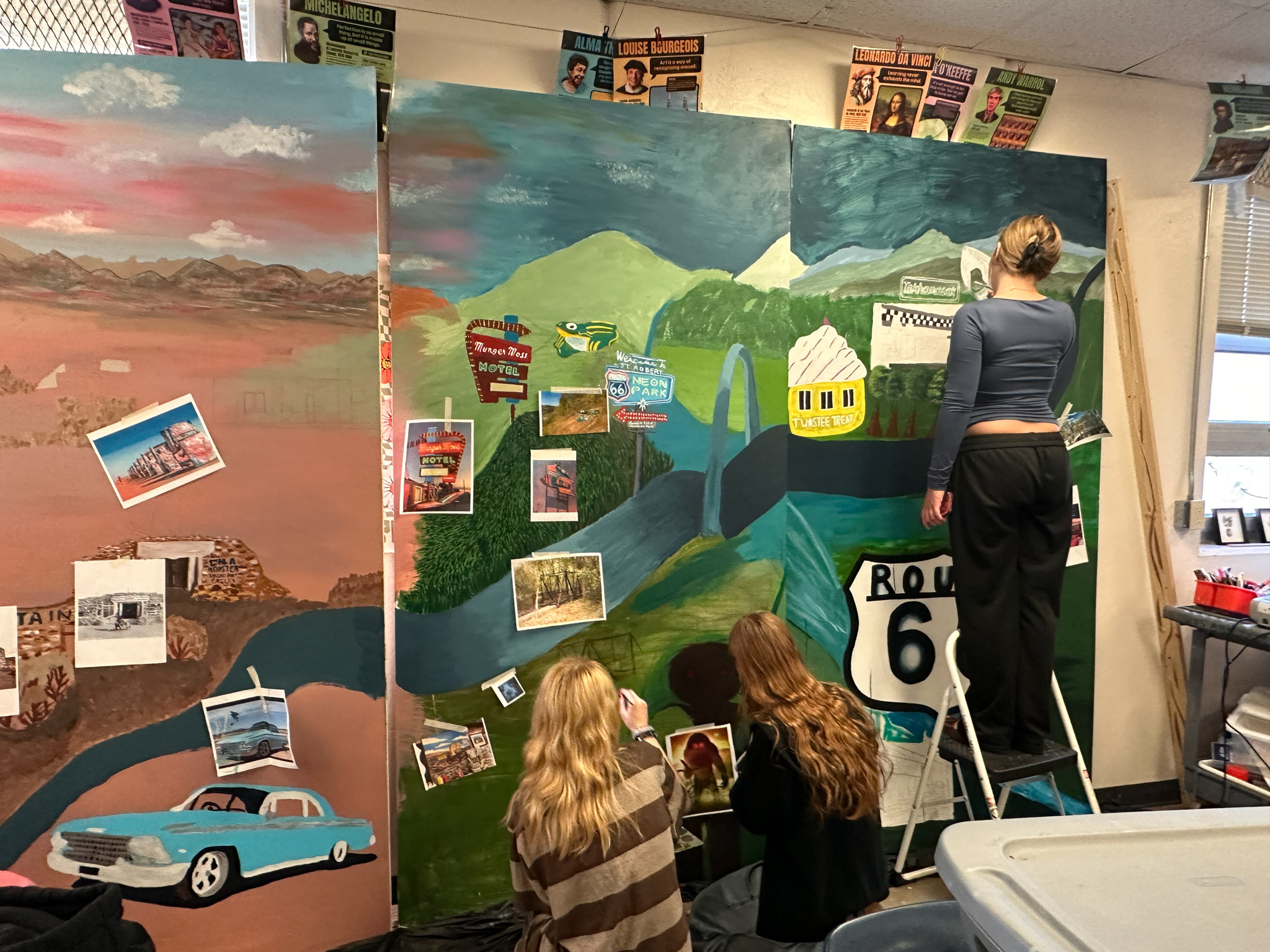 Three female students paint a mural